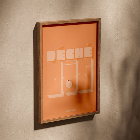 Affiche péché mignon, affiche dans un cadre en chêne posé de biais sur un mur texturé