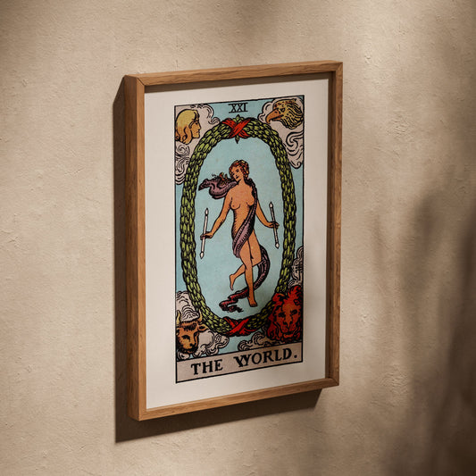 Le Monde - Arcane XXI du Tarot Rider-Waite, affiche dans un cadre en chêne posé de biais sur un mur texturé