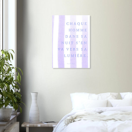 Minimalist bedroom with white bedding, plant, and French quote art print on wall