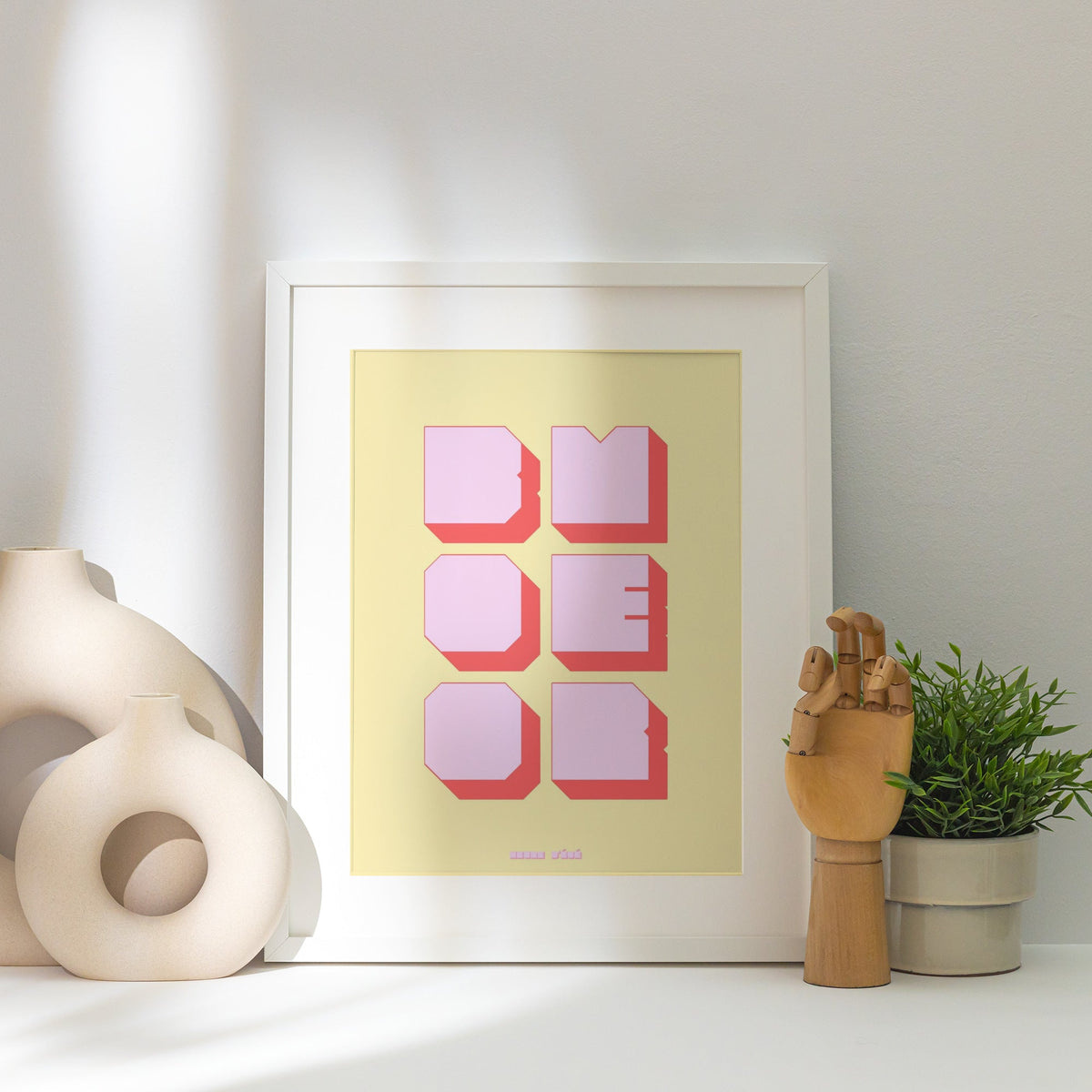 Affiche graphique Boomer, affiche encadrée posée près d'un vase blanc, lumière rasante