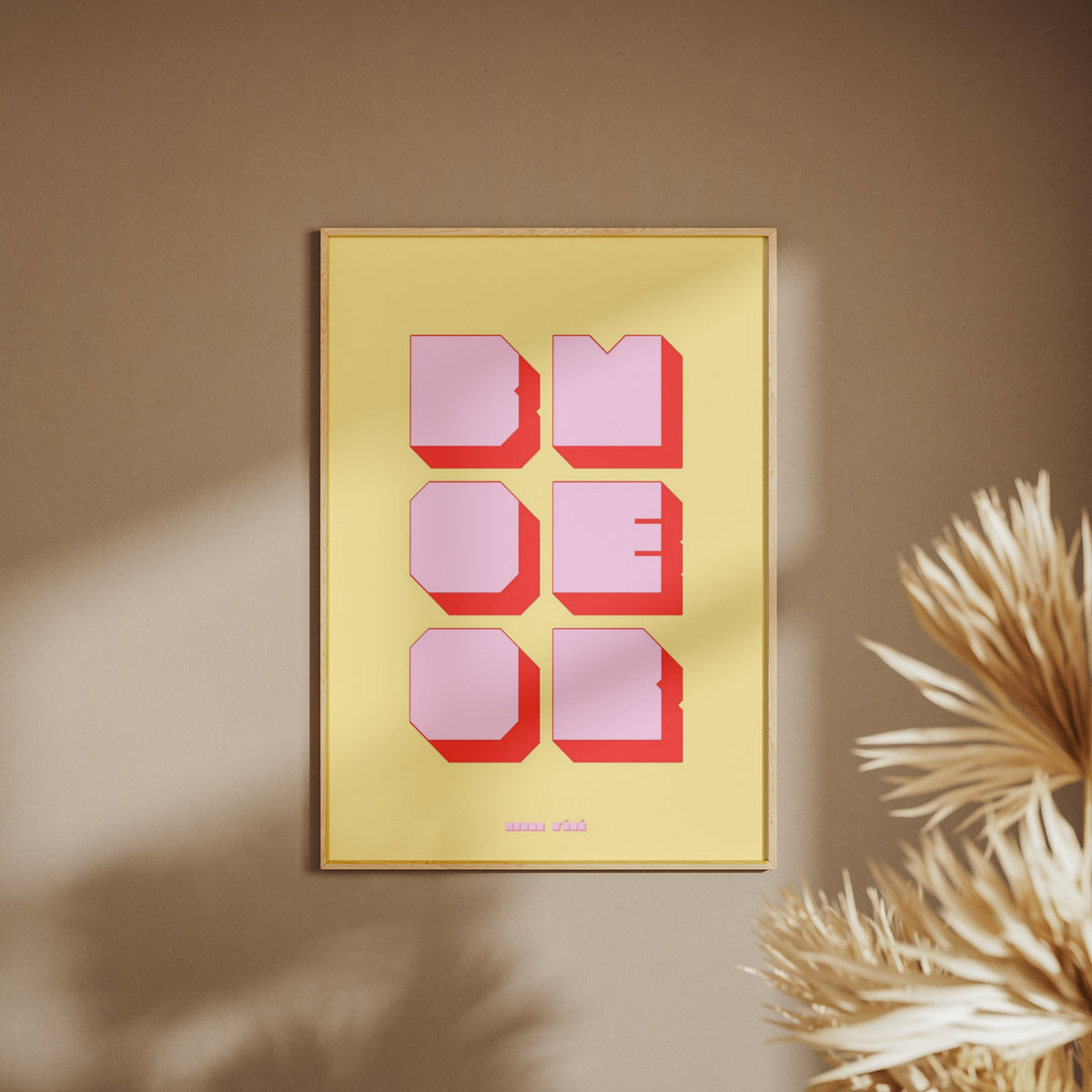 Affiche graphique Boomer, affiche encadrée sur un mur beige, pampas au premier plan