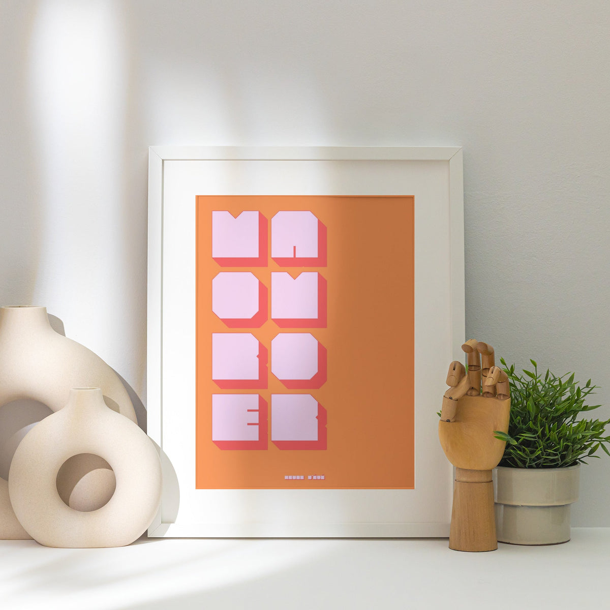 Affiche graphique More Amor, affiche encadrée posée près d'un vase blanc, lumière rasante