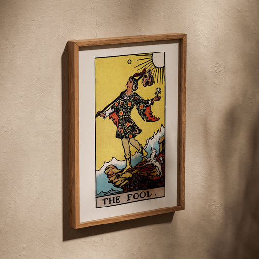 Le Mat - Arcane 0 du Tarot Rider-Waite, affiche dans un cadre en chêne posé de biais sur un mur texturé