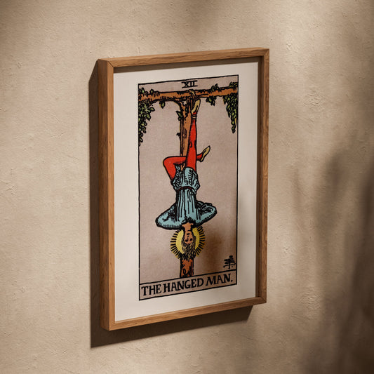 Le Pendu - Arcane XII du Tarot Rider-Waite, affiche dans un cadre en chêne posé de biais sur un mur texturé
