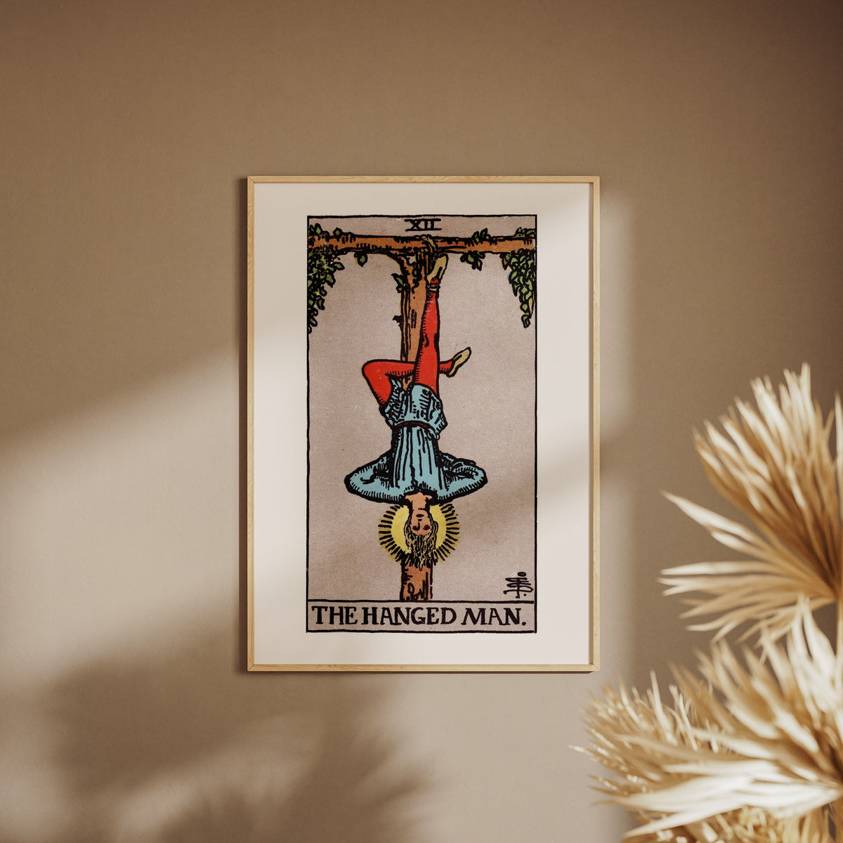 Arcana XII - The Hanged Man - Rider-Waite-Smith Tarot Poster, framed poster on a beige wall, pampas grass in the foreground