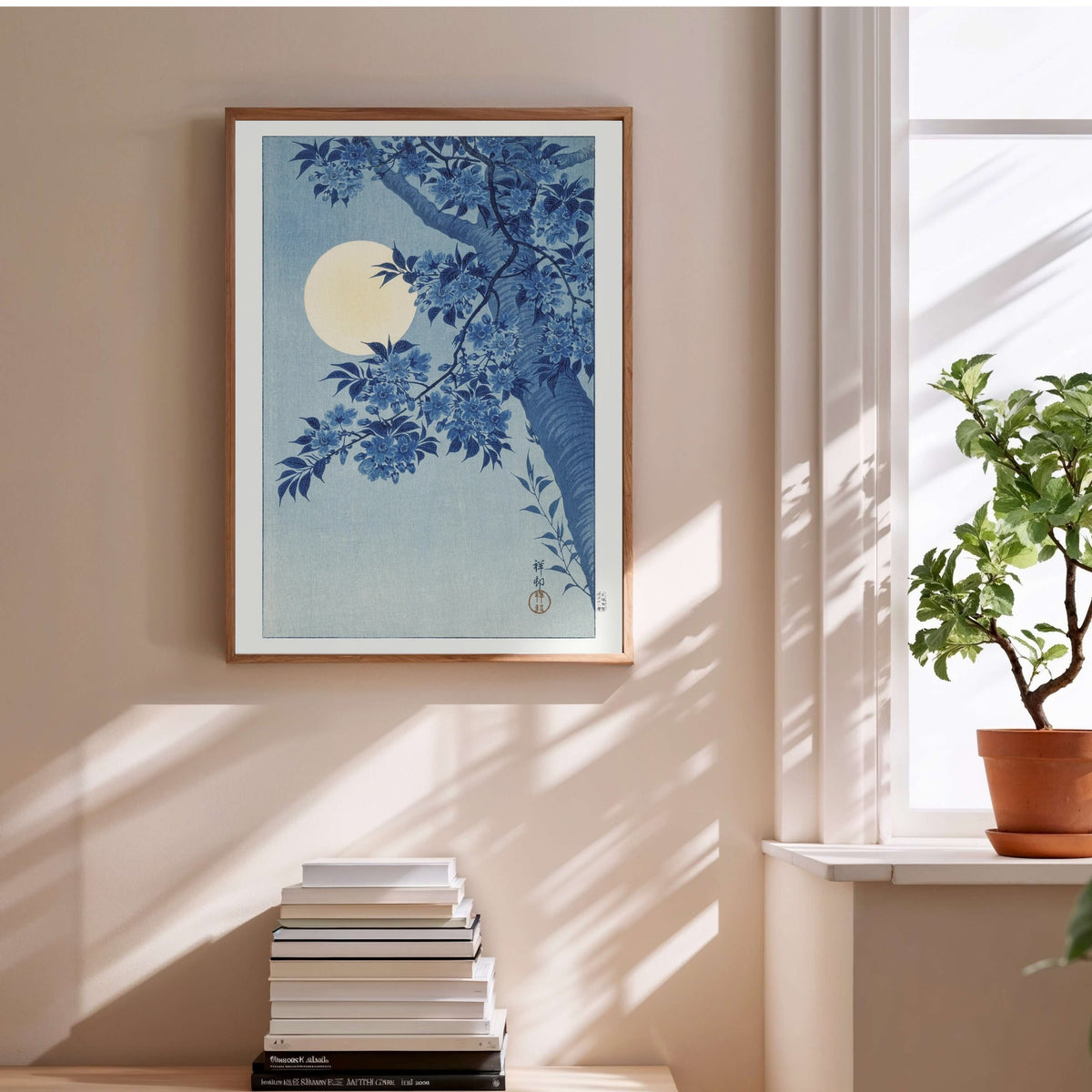 Cerisiers et Lune - Ohara Koson - Affiche Estampe Japonaise, affiche encadrée au-dessus d'une pile de livres