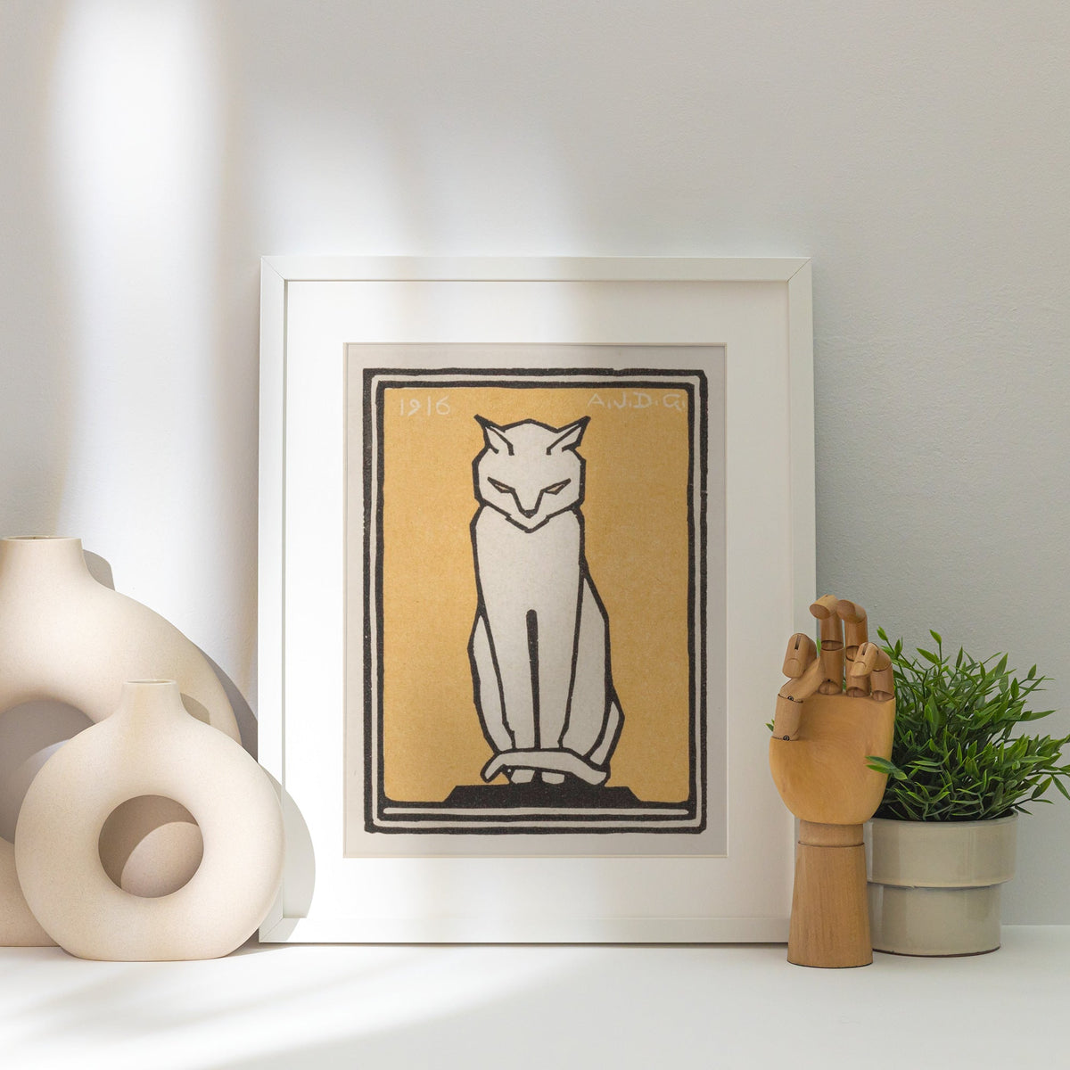 Chat Blanc Fond Jaune - Julie de Graag - Affiche Animaux, affiche encadrée posée près d'un vase blanc, lumière rasante