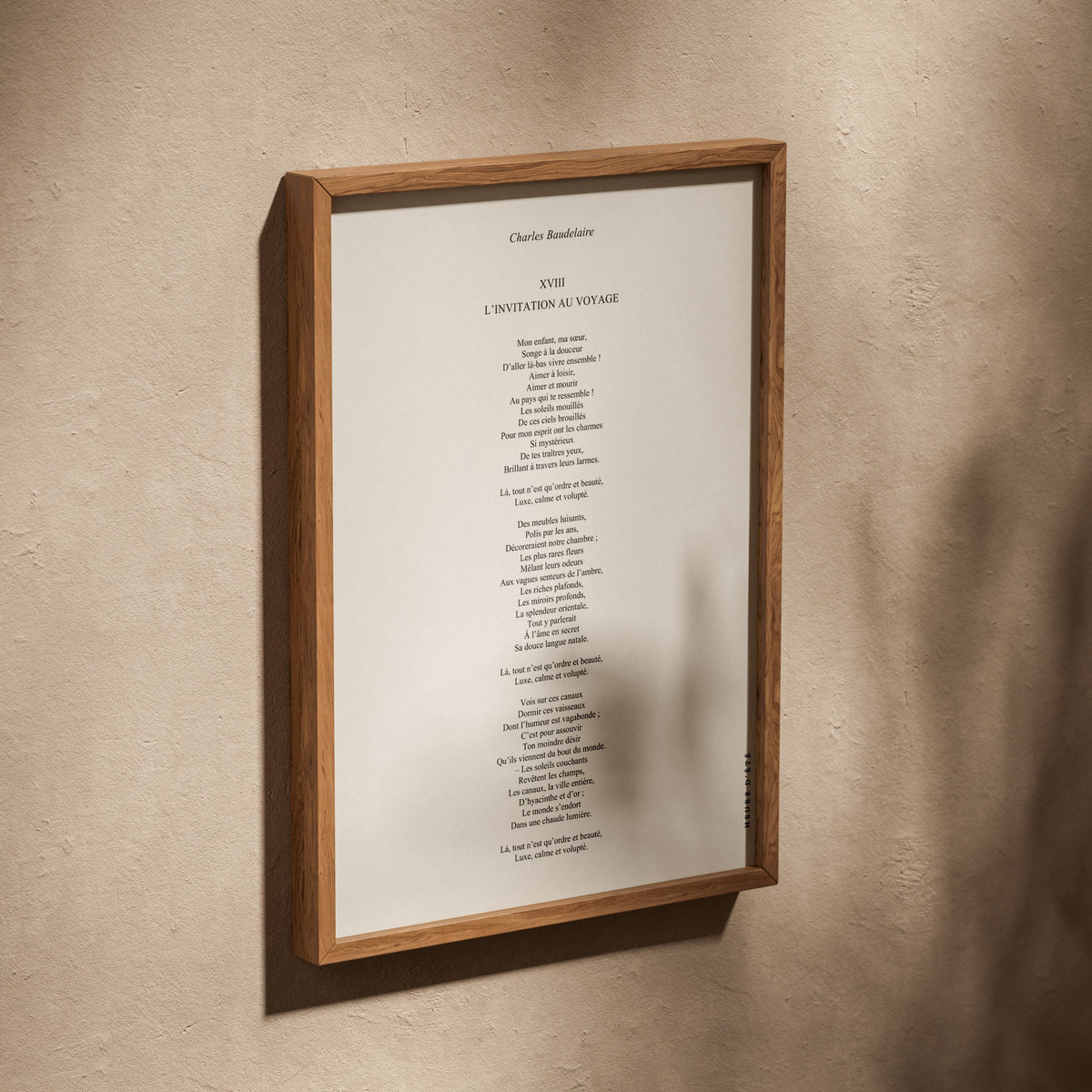 Affiche L'Invitation au voyage, poster poème Baudelaire, affiche dans un cadre en chêne posé de biais sur un mur texturé