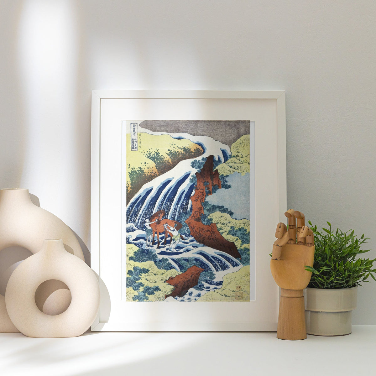 Cascade de Yoshino - Hokusai - Affiche Estampe Japonaise, affiche encadrée posée près d'un vase blanc, lumière rasante