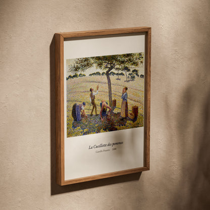 La Cueillette des pommes, Camille Pissarro, affiche dans un cadre en chêne posé de biais sur un mur texturé