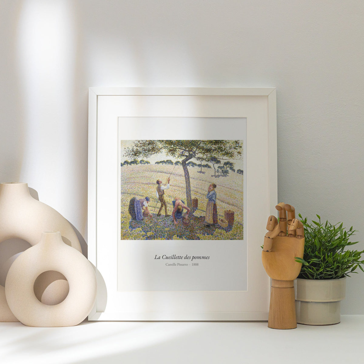 La Cueillette des pommes, Camille Pissarro, affiche encadrée posée près d'un vase blanc, lumière rasante