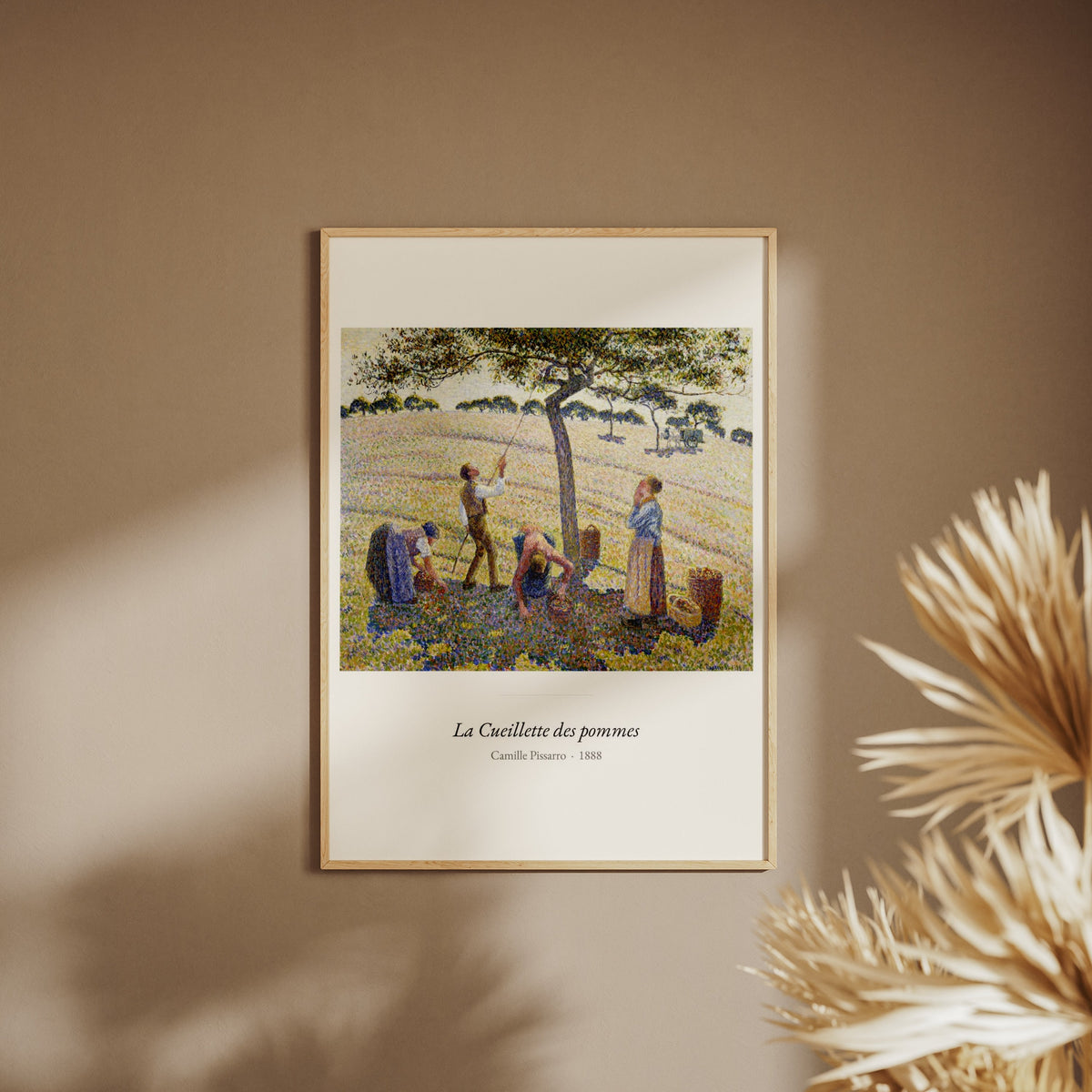 La Cueillette des pommes, Camille Pissarro, affiche encadrée sur un mur beige, pampas au premier plan