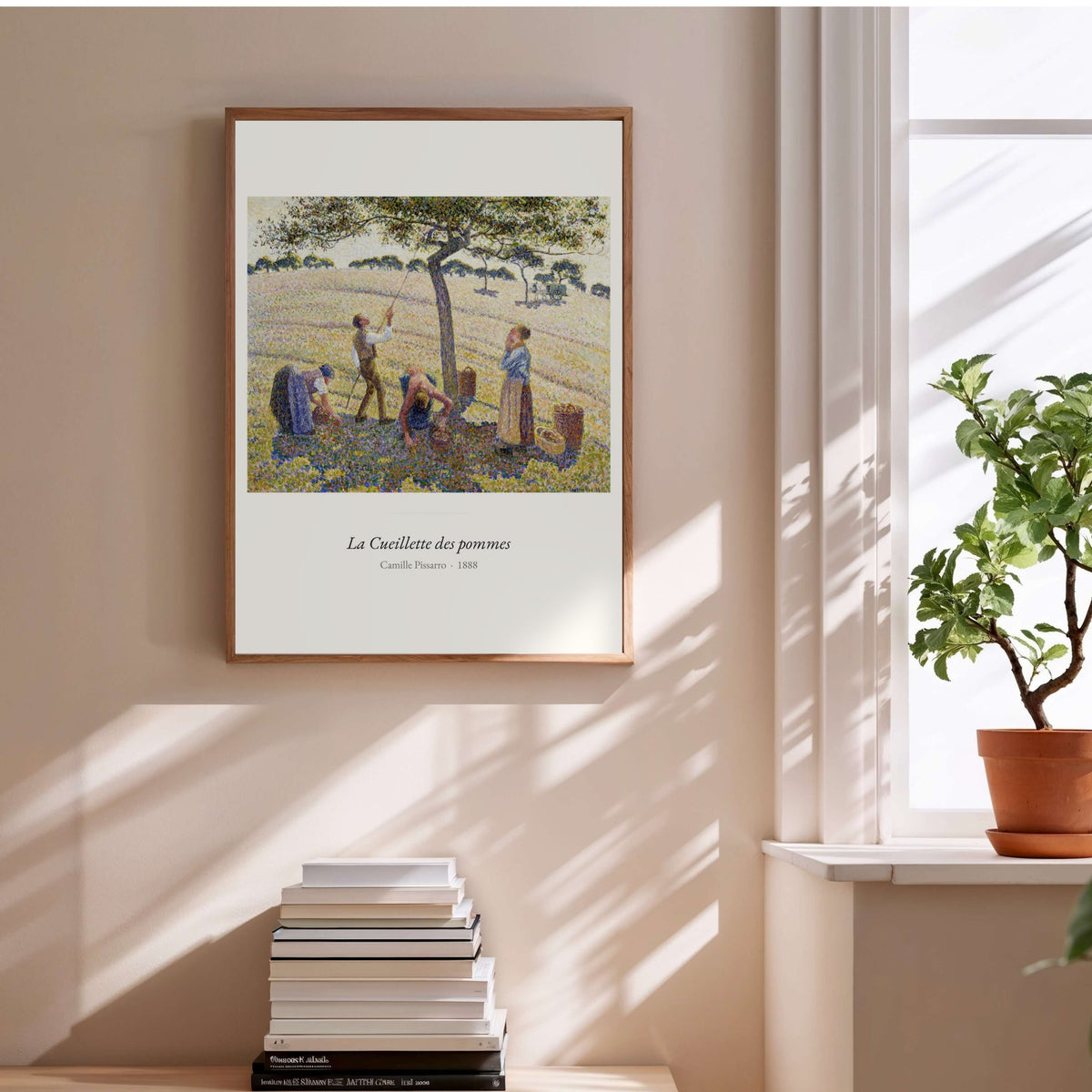 La Cueillette des pommes, Camille Pissarro, affiche encadrée au-dessus d'une pile de livres