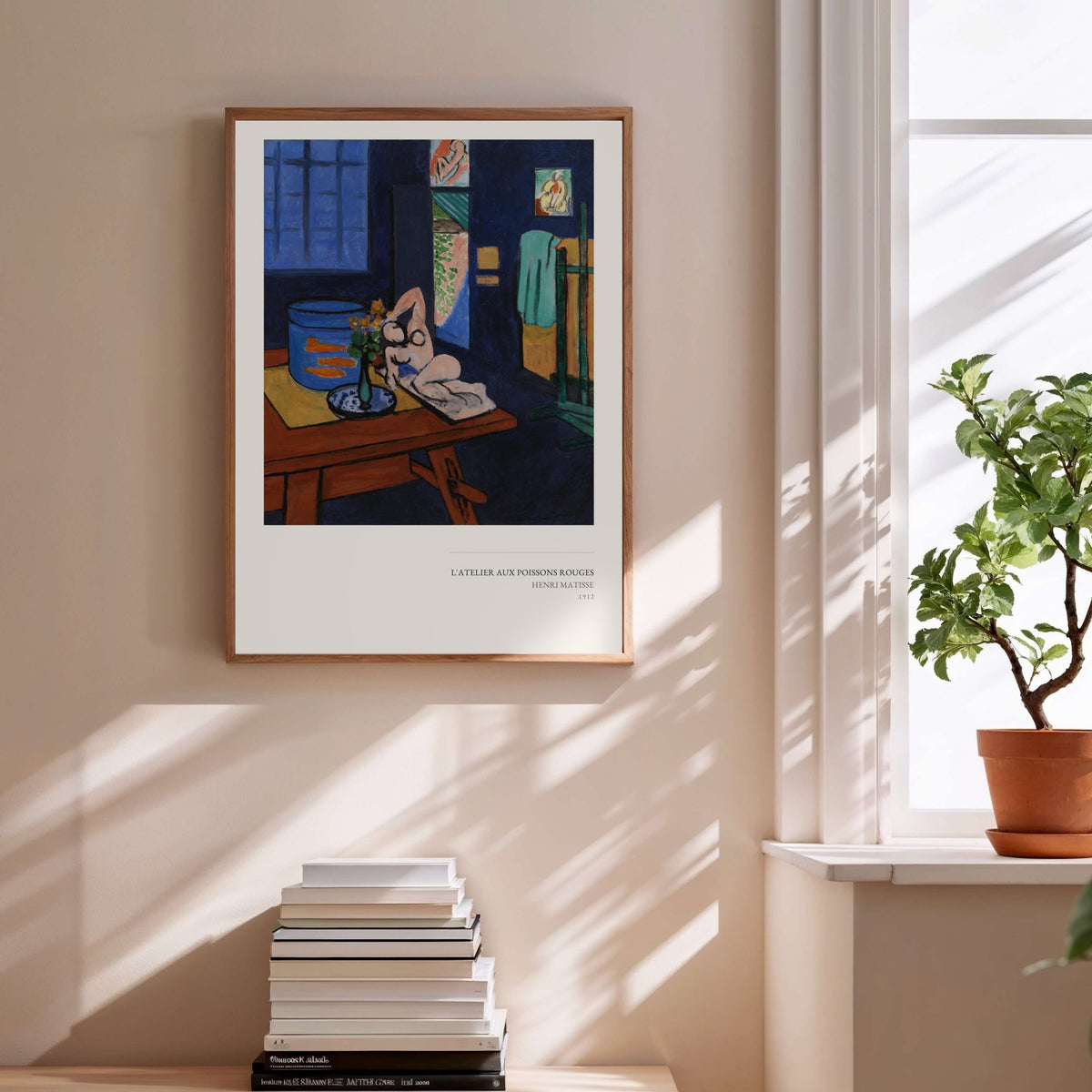 L'Atelier aux Poissons Rouges - Henri Matisse, affiche encadrée au-dessus d'une pile de livres