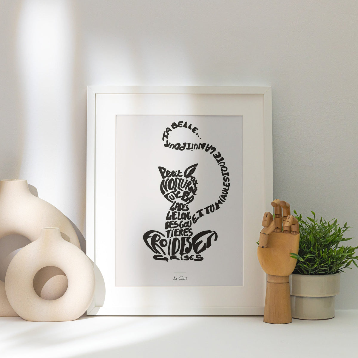Le Chat | Affiche Calligramme inspirée d'Apollinaire, affiche encadrée posée près d'un vase blanc, lumière rasante