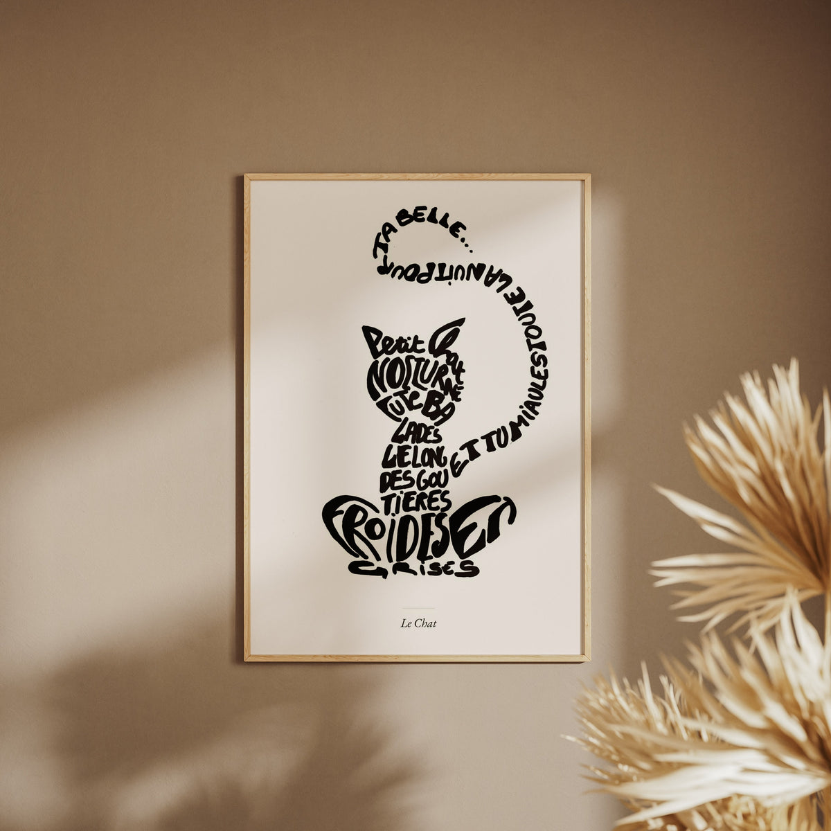 Le Chat | Affiche Calligramme inspirée d'Apollinaire, affiche encadrée sur un mur beige, pampas au premier plan