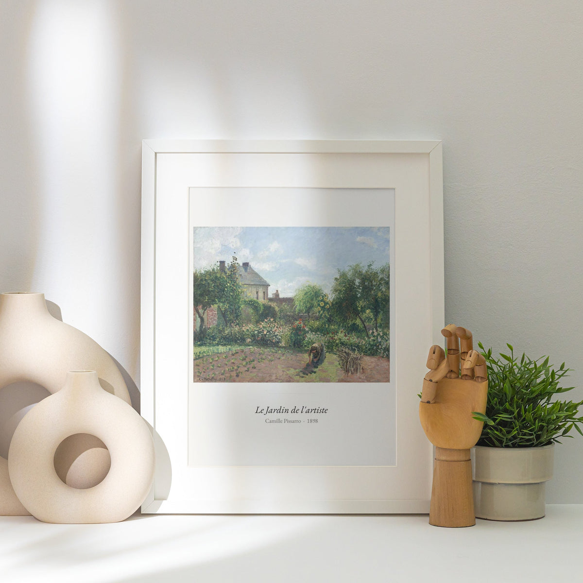 Le Jardin de l'artiste, Camille Pissarro, affiche encadrée posée près d'un vase blanc, lumière rasante