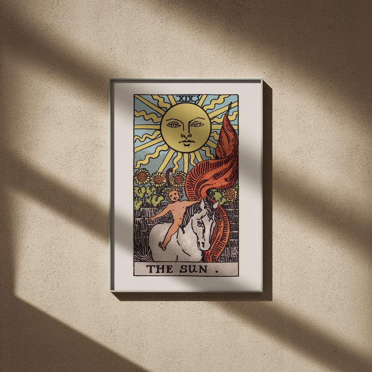 Le Soleil, arcane XIX du tarot Rider-Waite en 50x70, encadré sur un mur beige, ombres de fenêtre