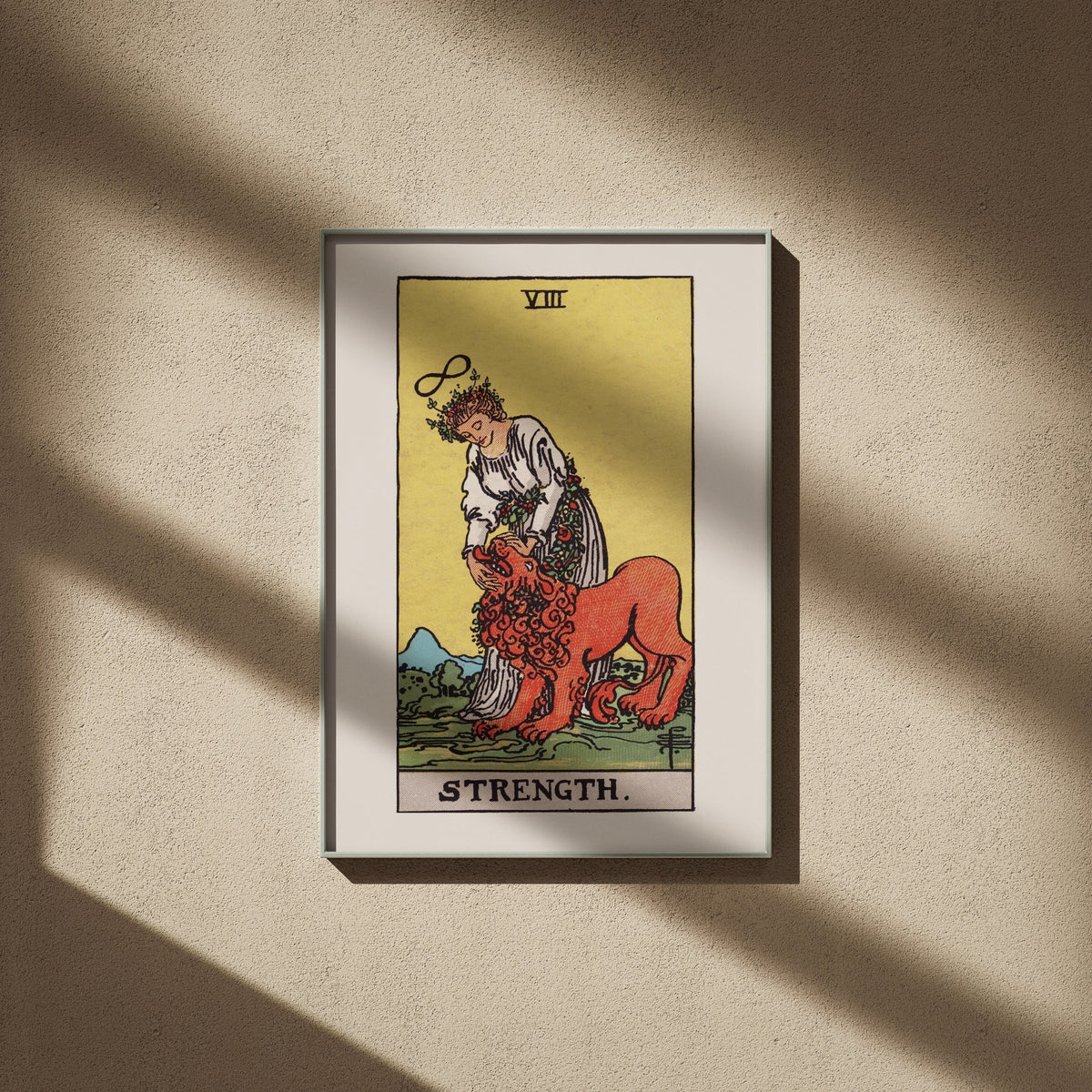La Force, arcane VIII du tarot Rider-Waite en 50x70, encadré sur un mur beige, ombres de fenêtre