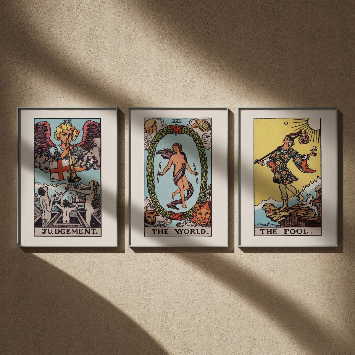 Triptyque tarot Rider-Waite en 50x70 : Le Jugement, Le Monde et Le Mat, encadrés côte à côte sur un mur beige