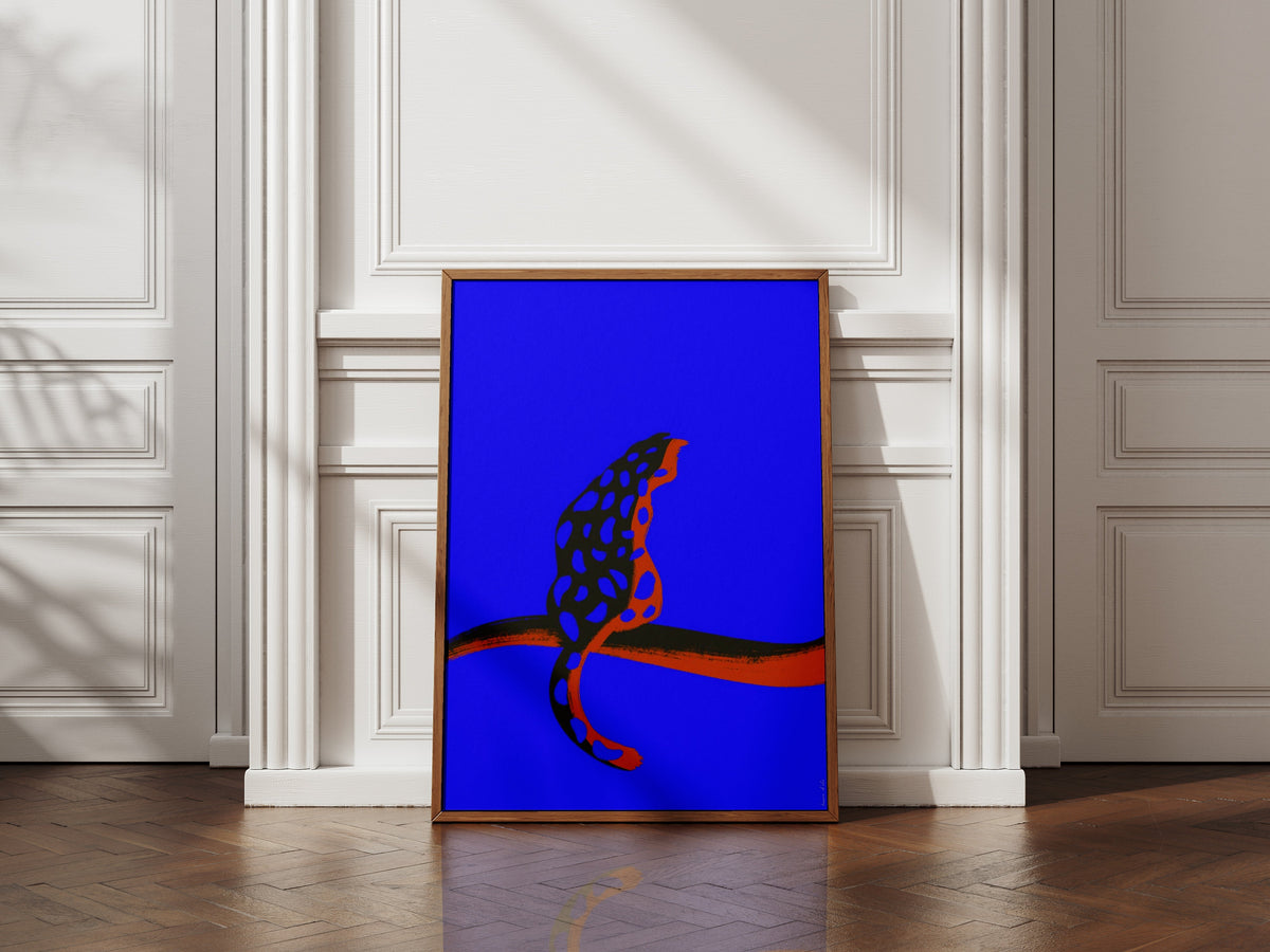 Affiche Burning Blue, motif tacheté rouge et noir sur fond bleu électrique, cadre bois contre un mur à moulures